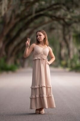 Teen girl in beige dress posing under St Augustine's historic tree canopy for professional family photography session