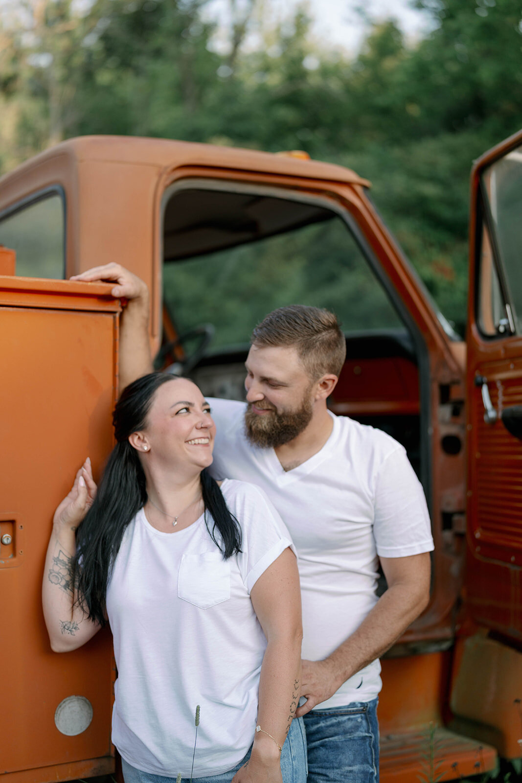 Kali and Joe walking through a sunlit open field on private property during their summer engagement session near Detroit.
