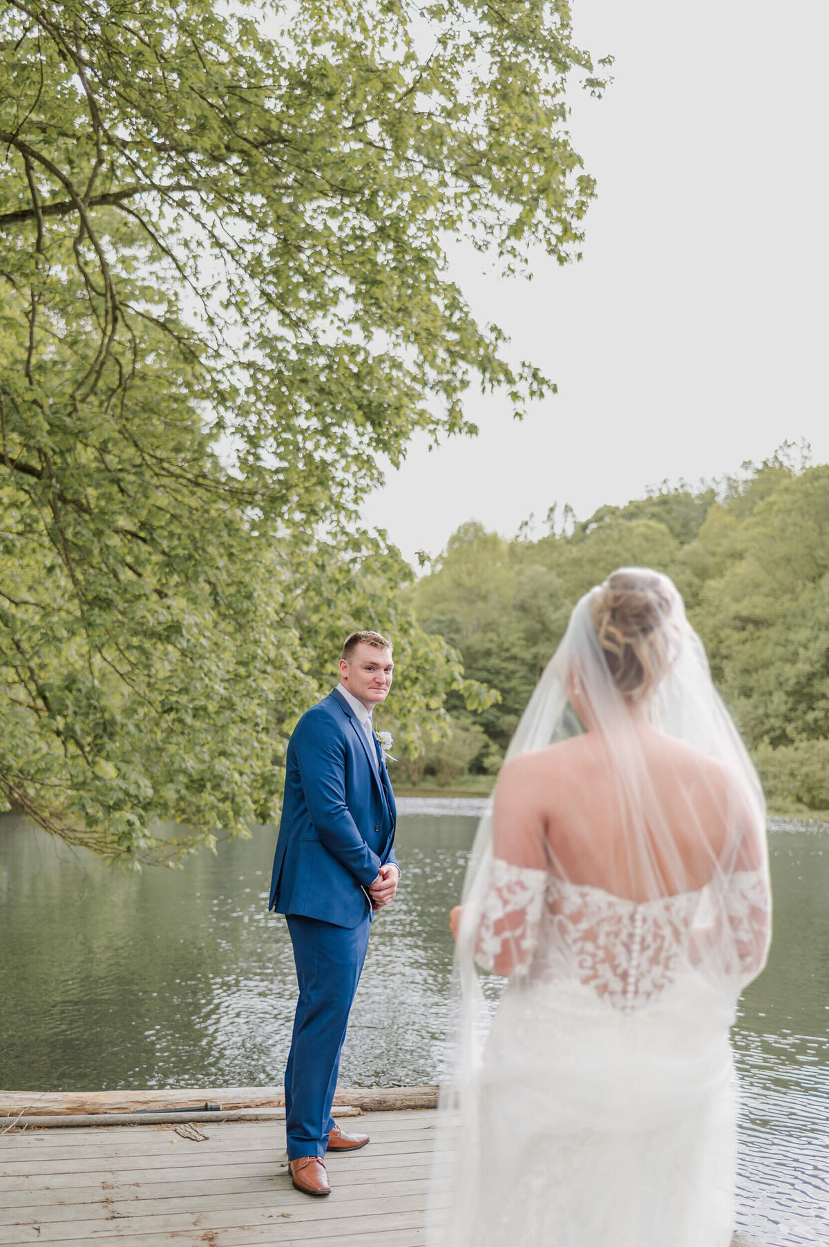 Bride and groom first look by the water, captured by timeless wedding photographer Bree Stewart of Lens Love Photography.