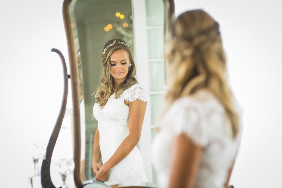 A bride glances at herself in the mirror as she gets ready for her wedding.