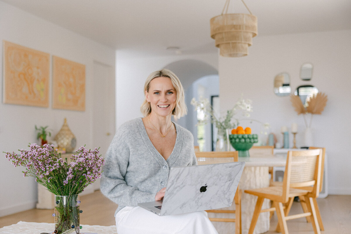 Zelda Green, money and mindset educator, entrepreneur and podcaster, leaning against the front door to a home smiling and welcoming
