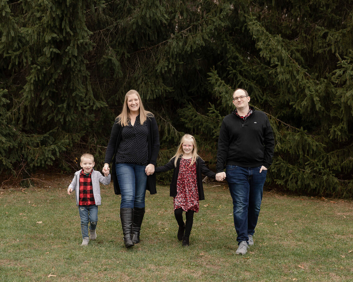 Dad, Mom and two children holding hands walking across a field.