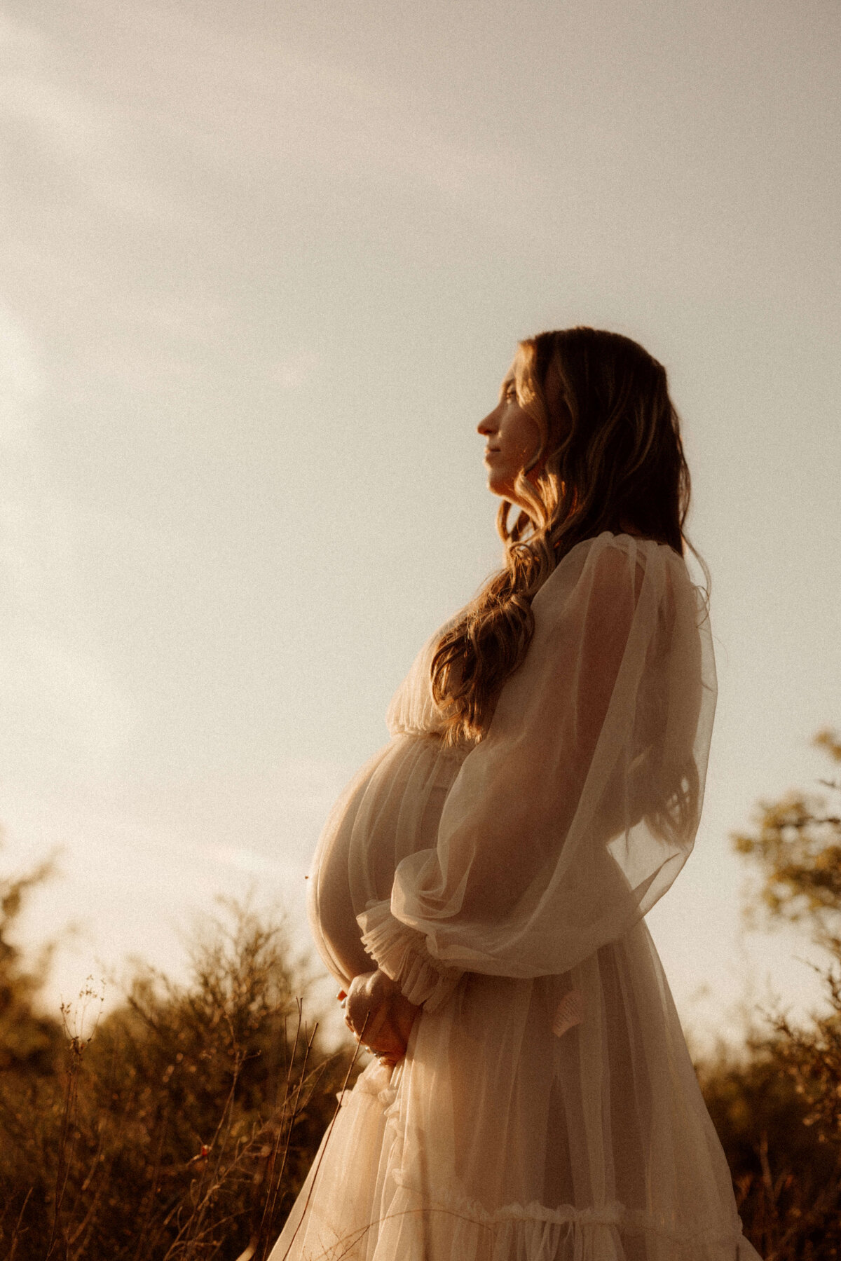 Expecting mother sitting by window during Franklin TN lifestyle maternity shoot