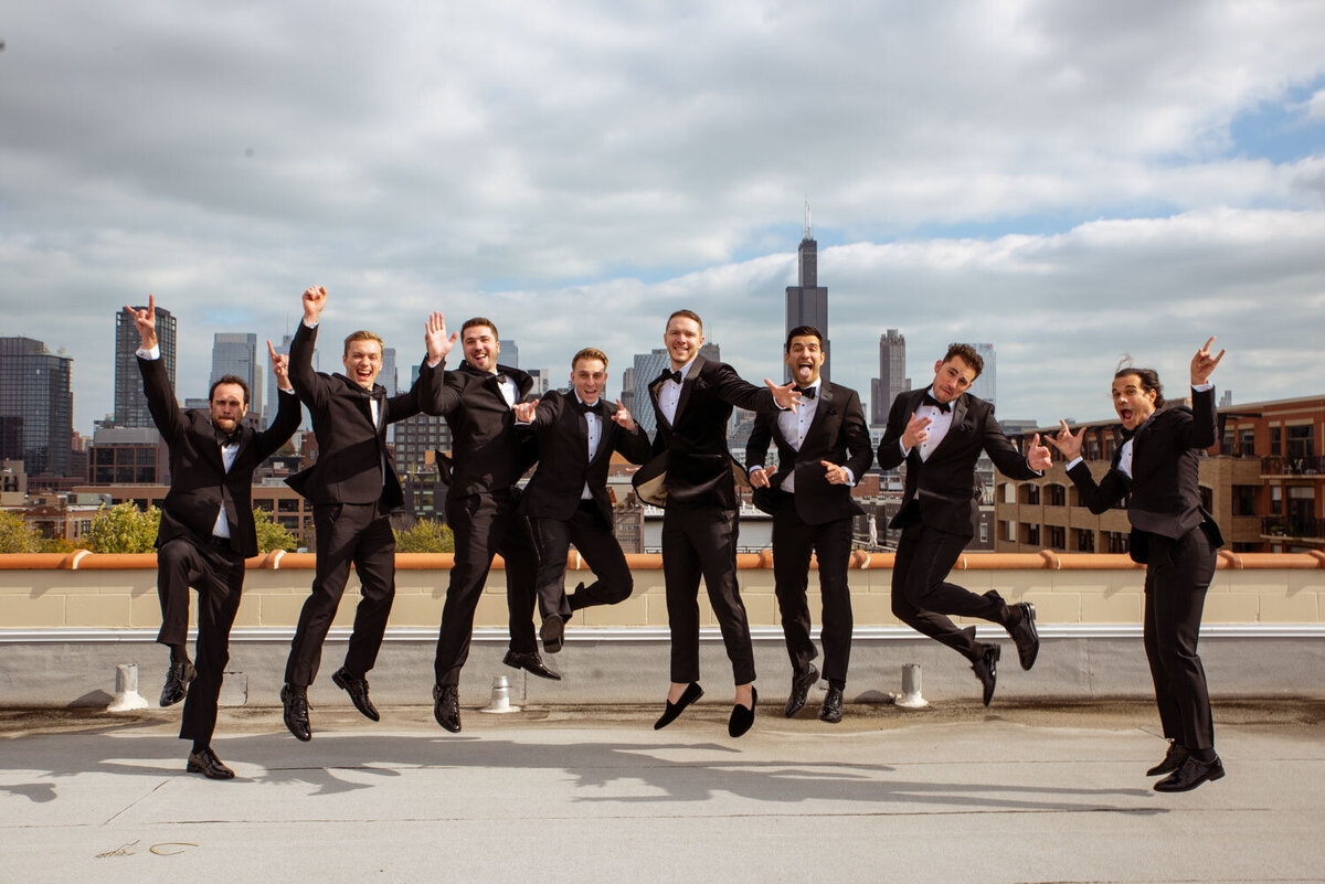 A group of men in tuxedos are jumping in the air
