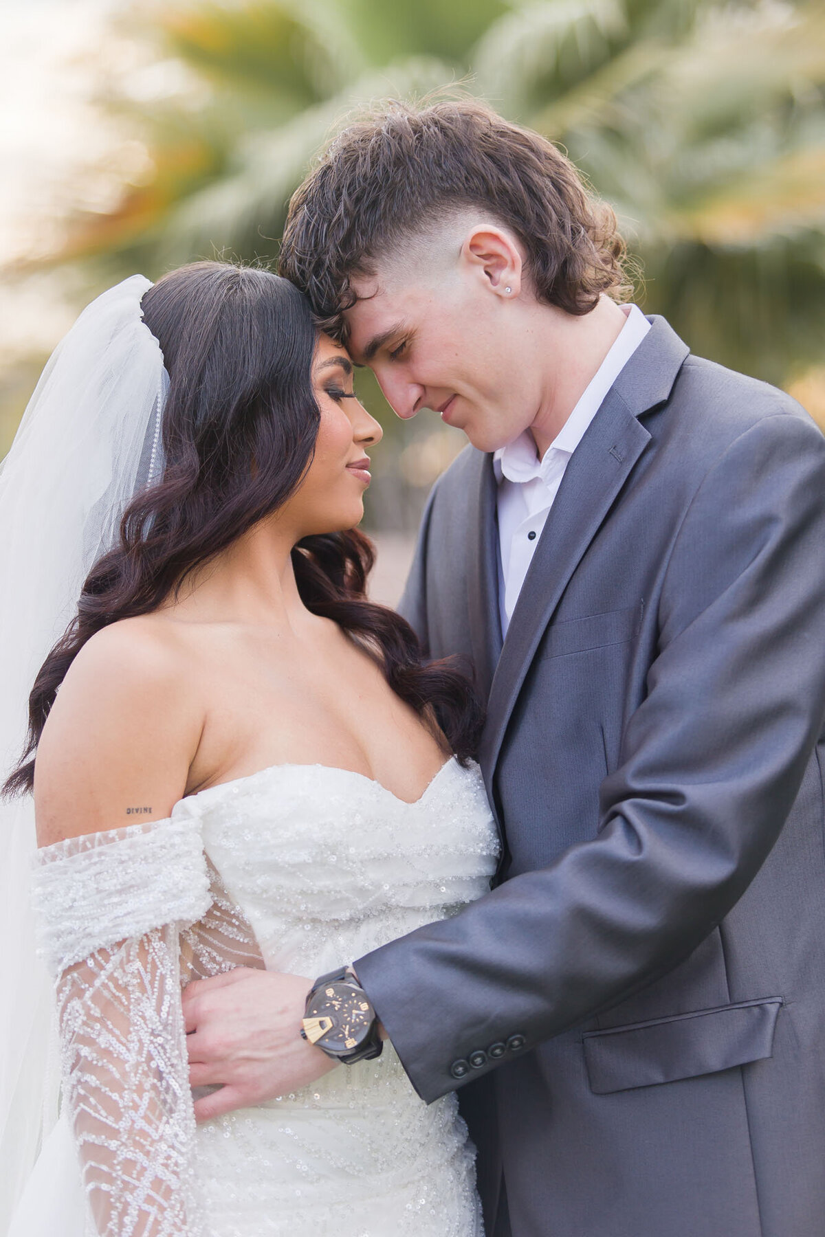 Bride and groom thoughtfully holding each other with foreheads together on their wedding day