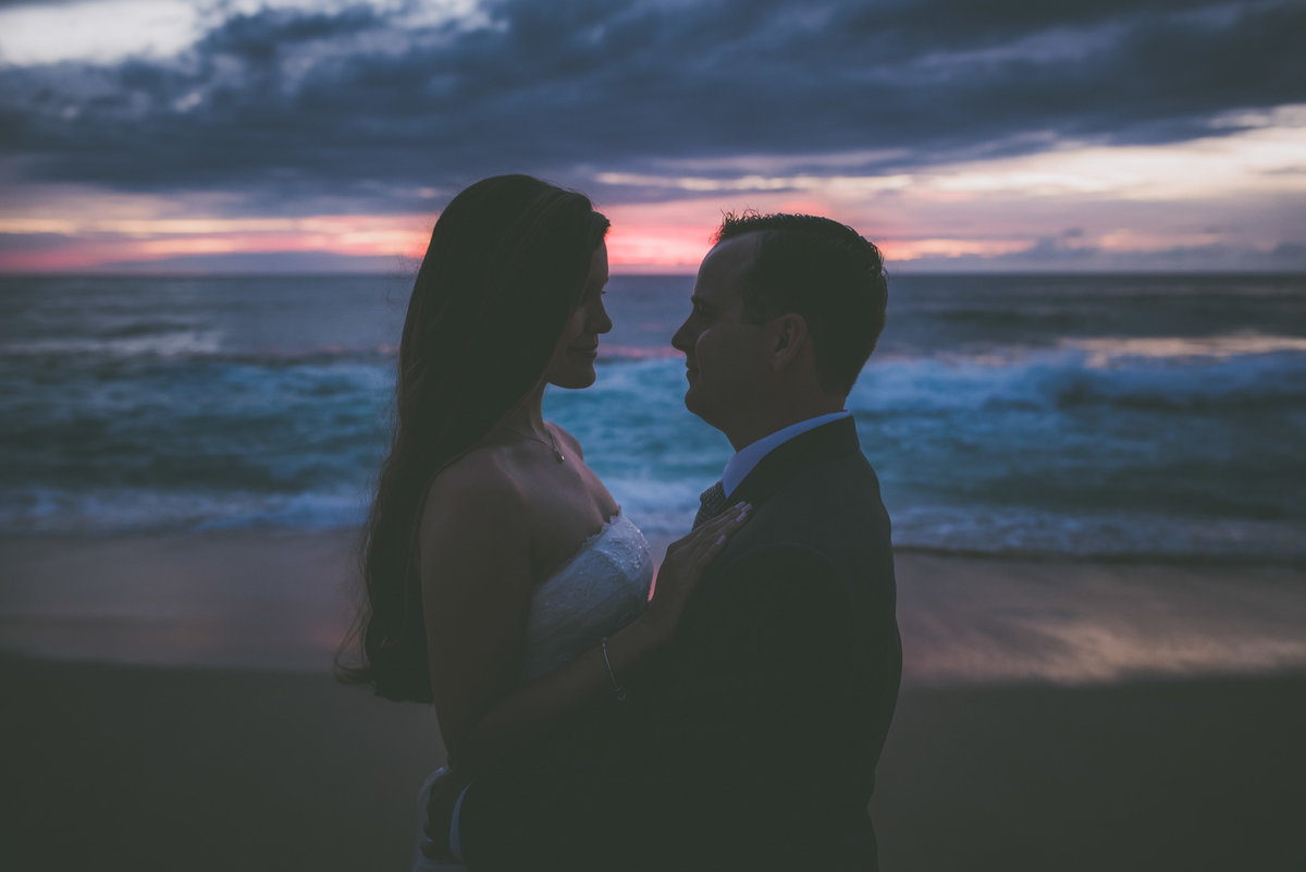 Newly weds gaze at each other during sunset on a beach in Oahu.
