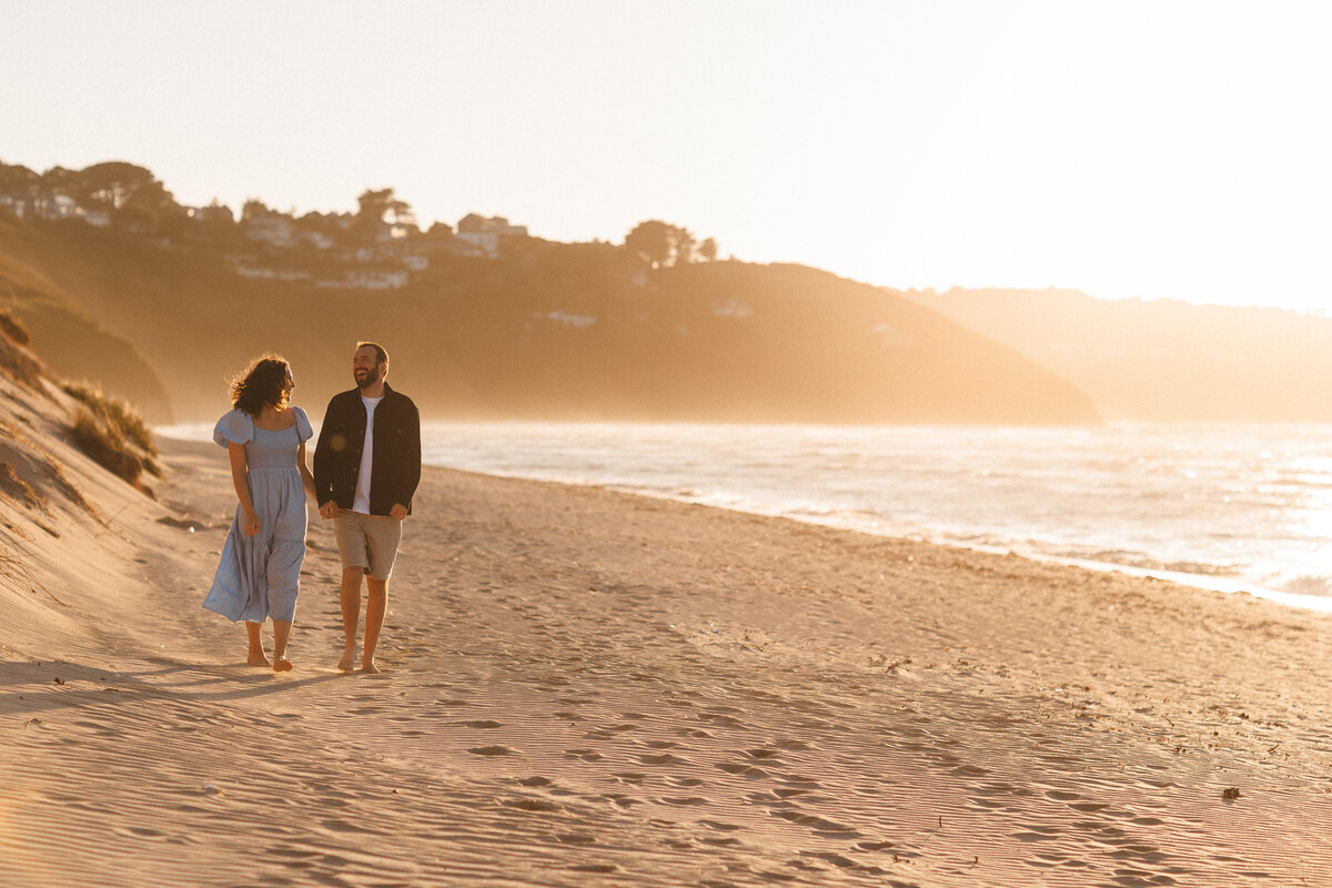 Photograph of a young  engaged couple at the beach in West Cornwall on a sunny day at sunset