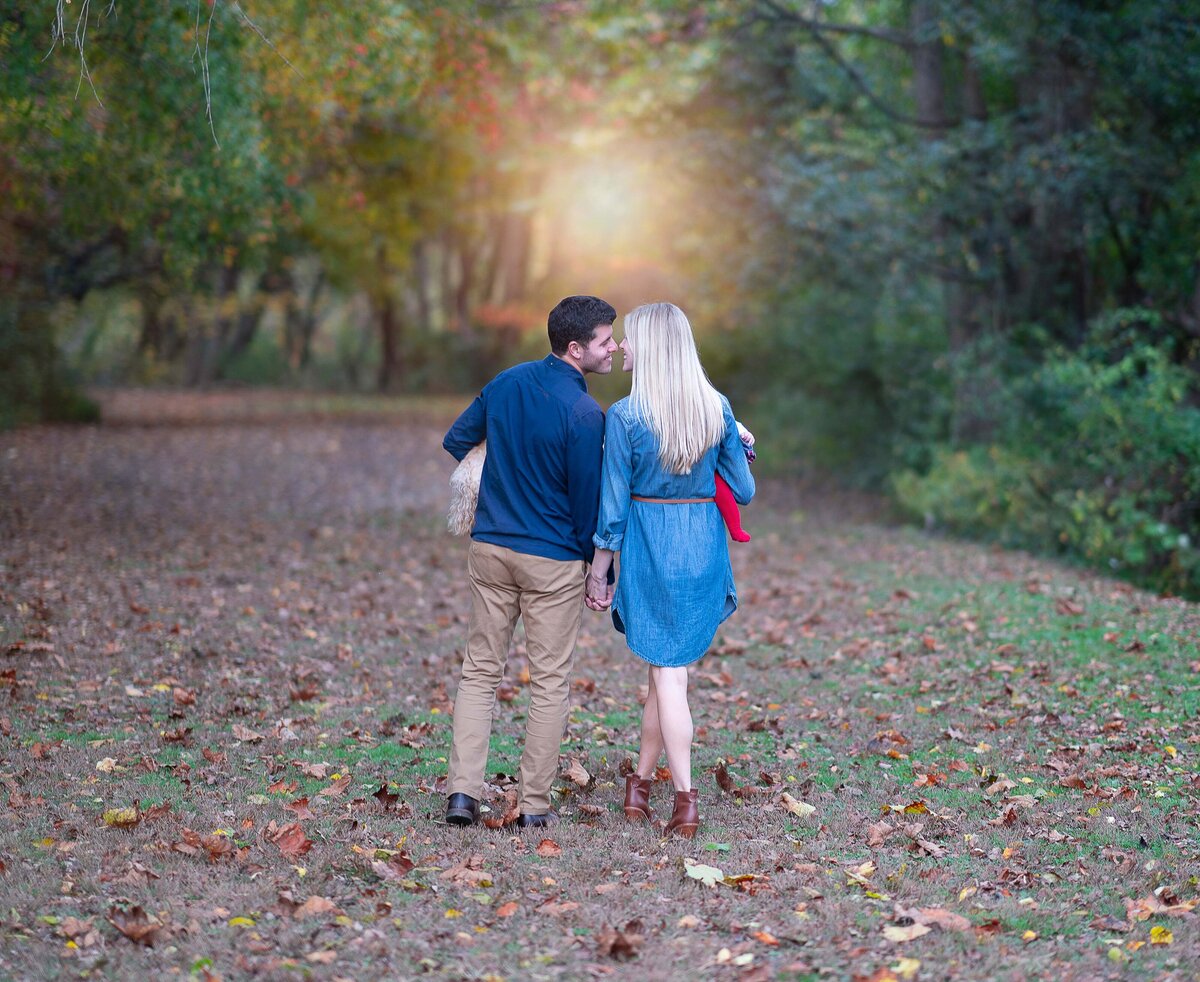 Couple are holding hands and walking away from the camera. Their arms are touching and noses touching about to kiss. Captured by Liza Nicole Photography, Philadelphia and Main Line family photographer.