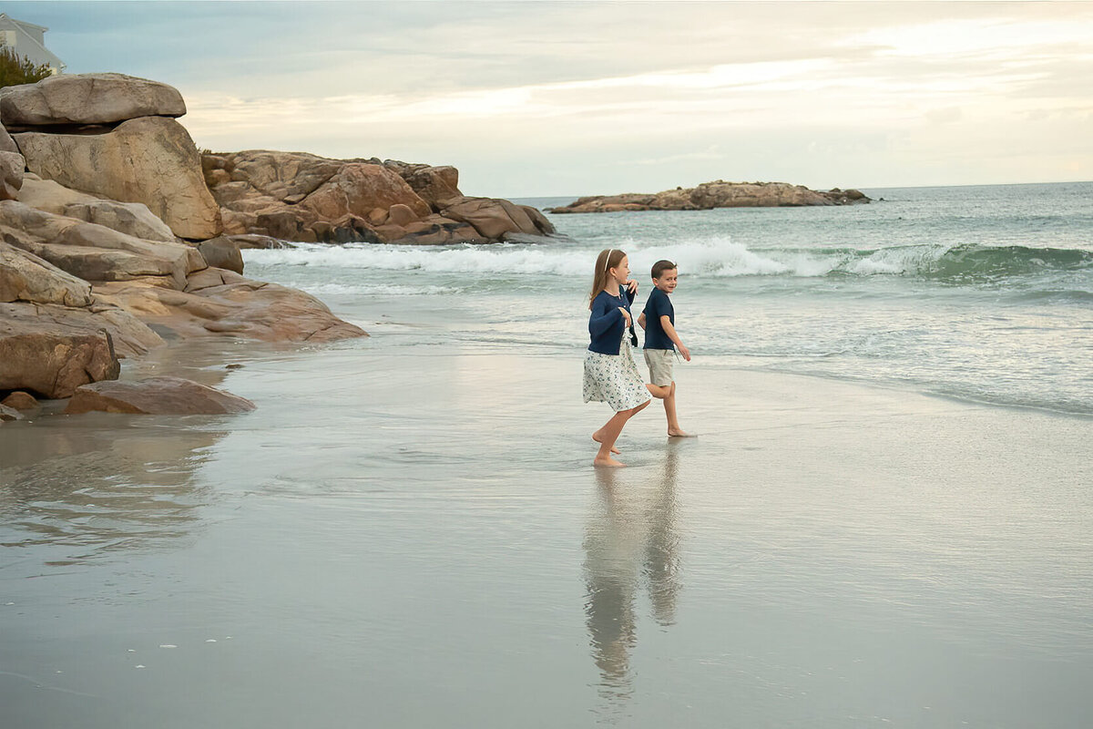 Siblings run into the ocean at Wingaersheek Beach.