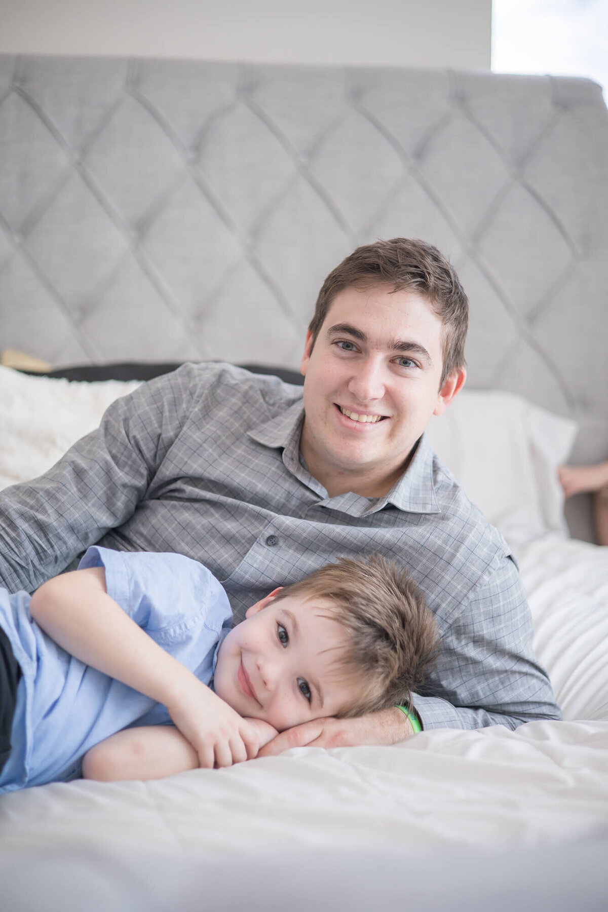 father and young son posing for a portrait on a bed