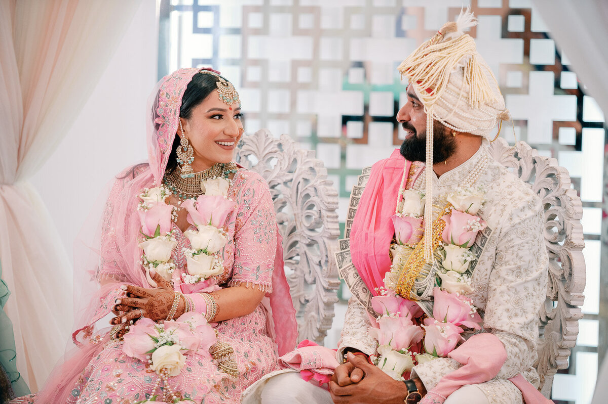 Bride & Groom sitting during Hindu wedding ceremony looking at each other and smiling