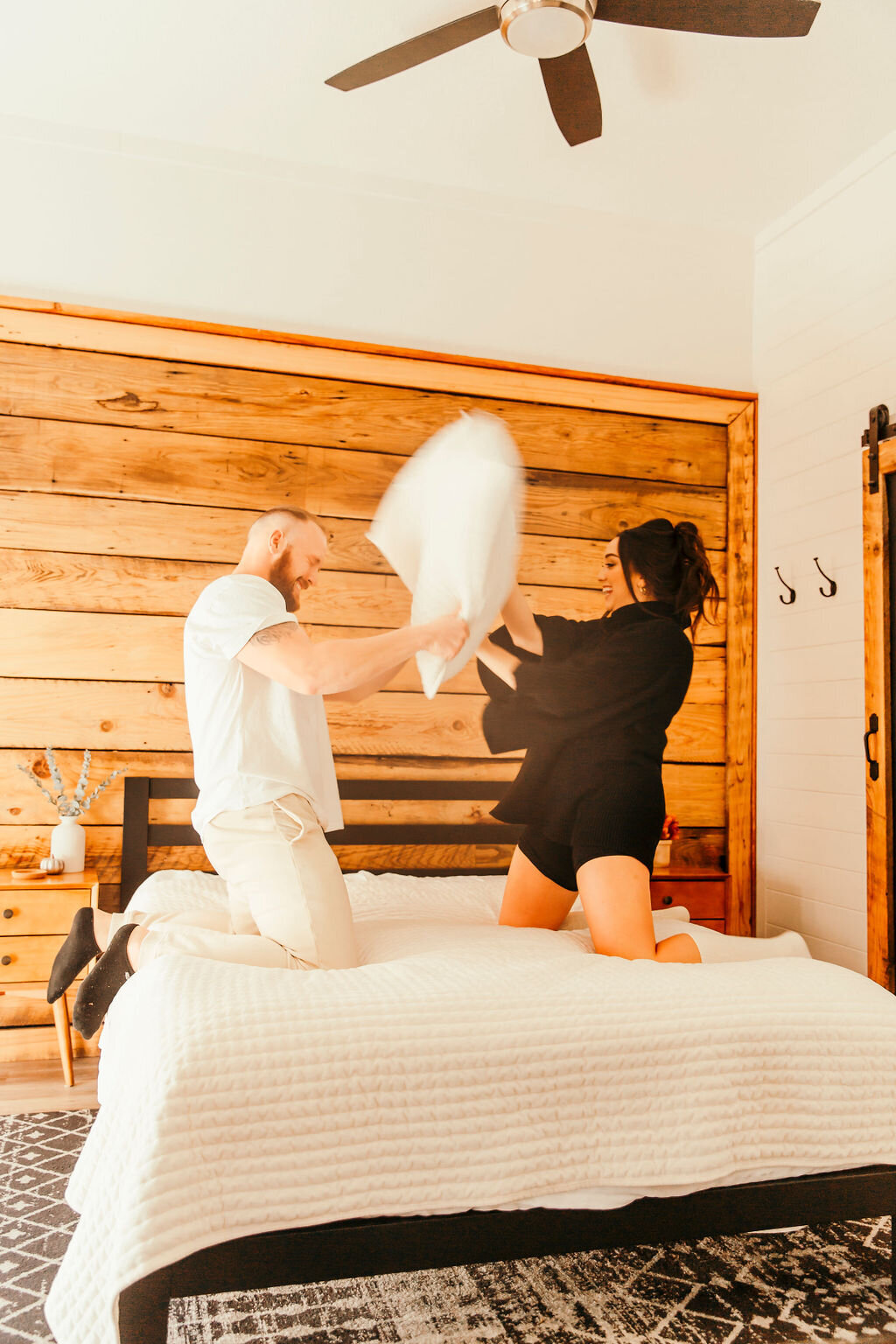 husband and wife pillow fighting in bed