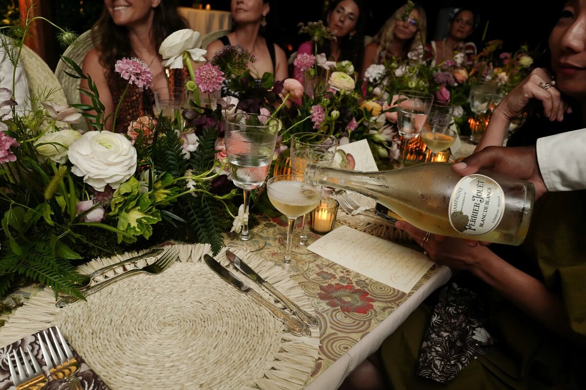 Close-up of woven chargers and romantic floral centerpieces at a dinner party, reception styling inspiration for Airlie Gardens