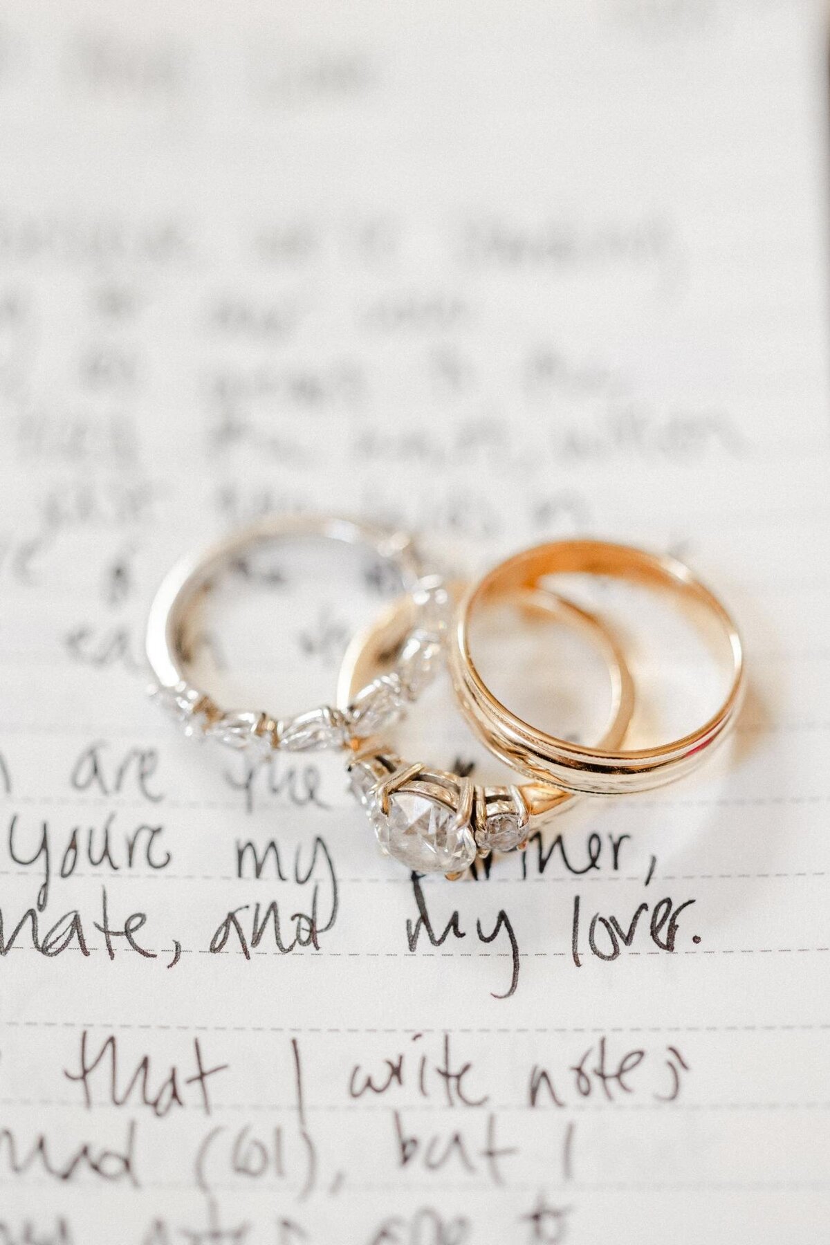 Two wedding rings atop a handwritten love note.