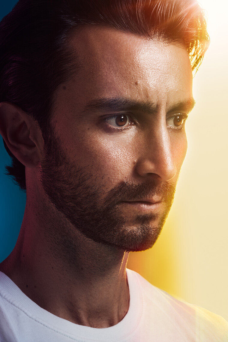 Dramatic portrait of Nathan against a yellow background with intense lighting, photographed by Ylva Erevall.