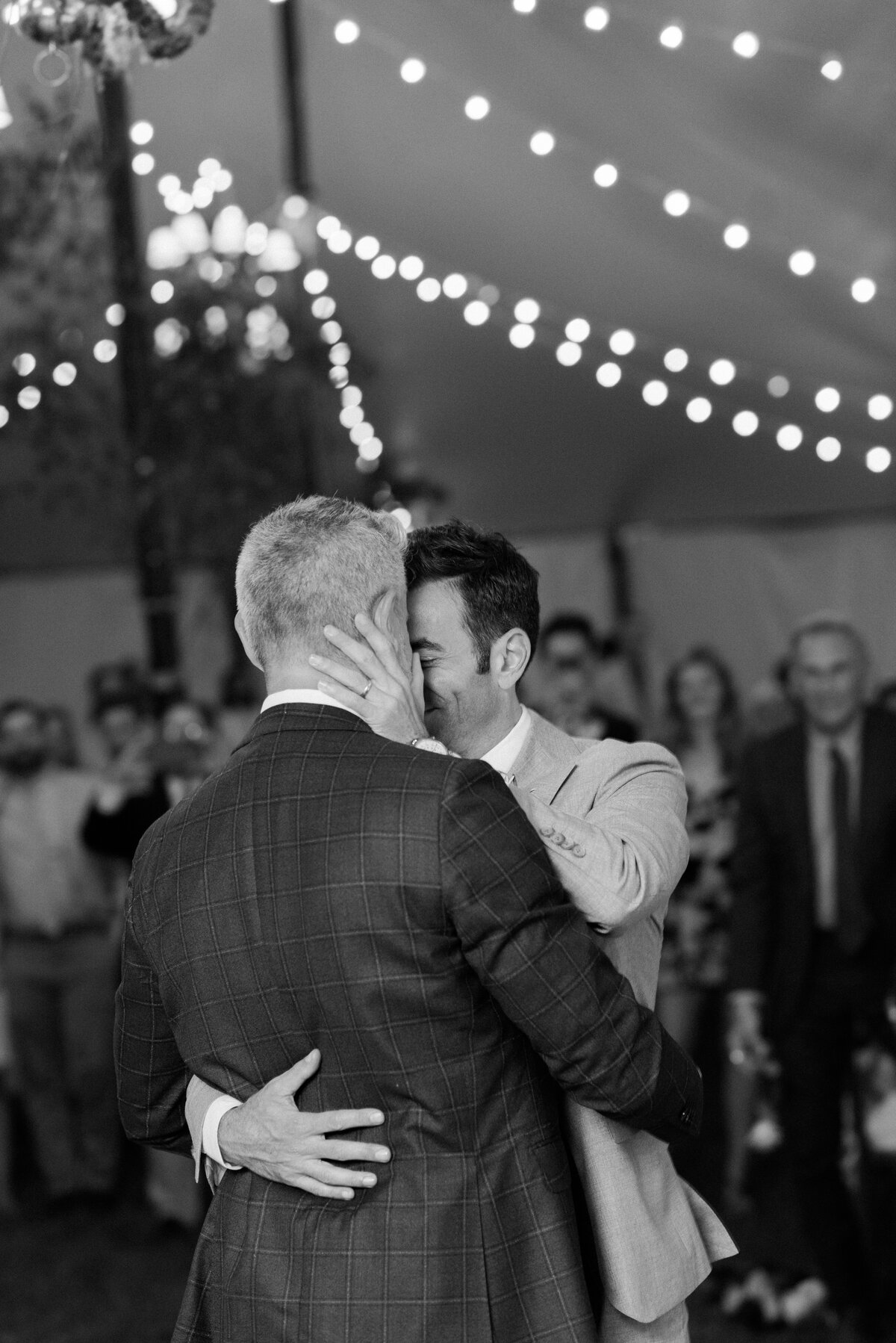 Groom rests his hand on his partner's face while dancing together