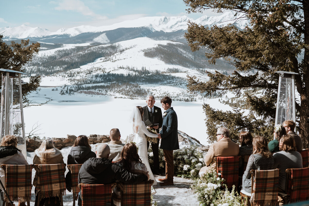 Couple exchanges vows with scenic snowy mountain backdrop at Sapphire Point ceremony.