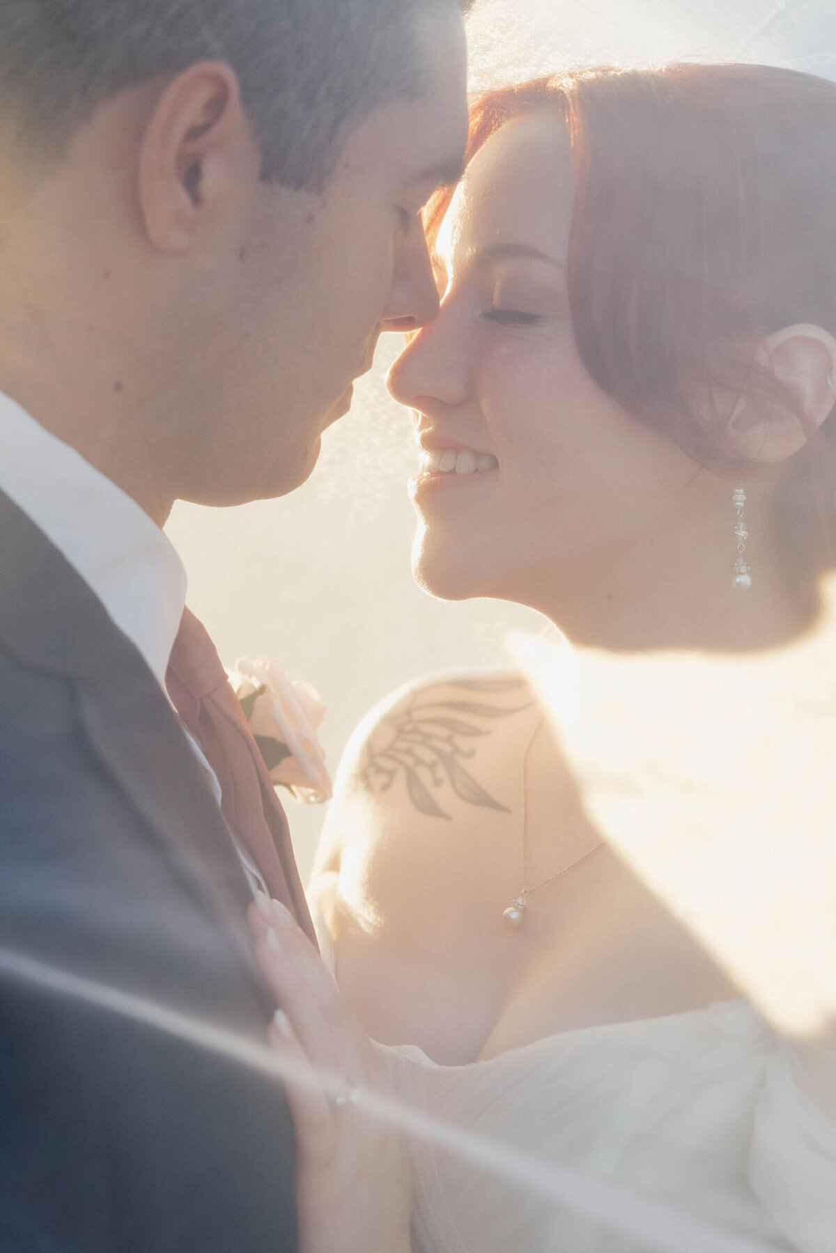 Bride and groom under her veil in the golden evening light
