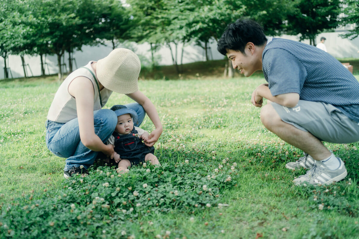 芝生で赤ちゃんと遊ぶ夫婦