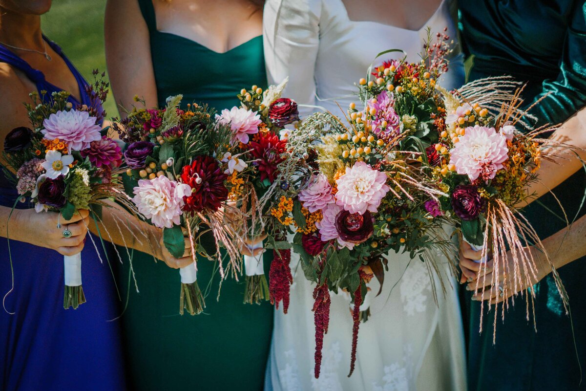 a bride with her bridesmaids holding their flowers together