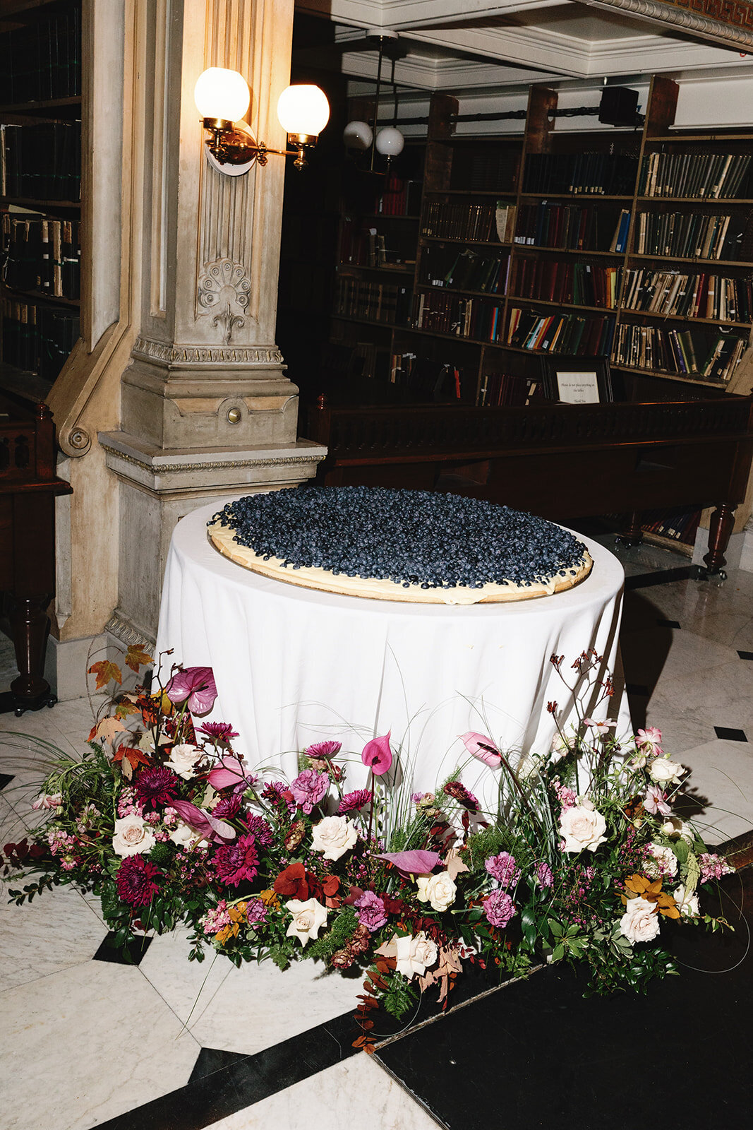 Italian blueberry wedding cake on white table with pink florals at the George Peabody Library