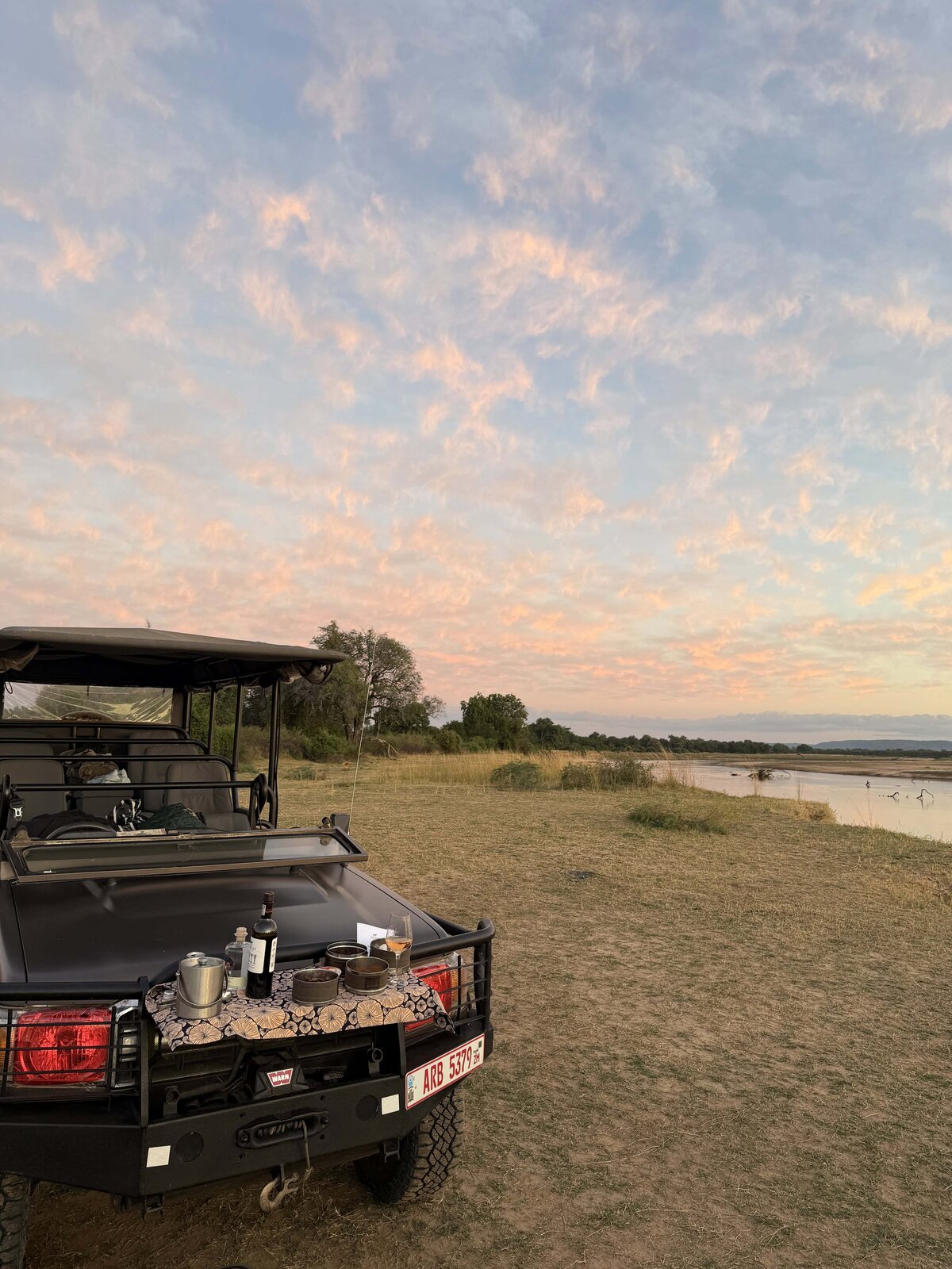tour jeep by a lake at sunrise with a picnic on the front of the car