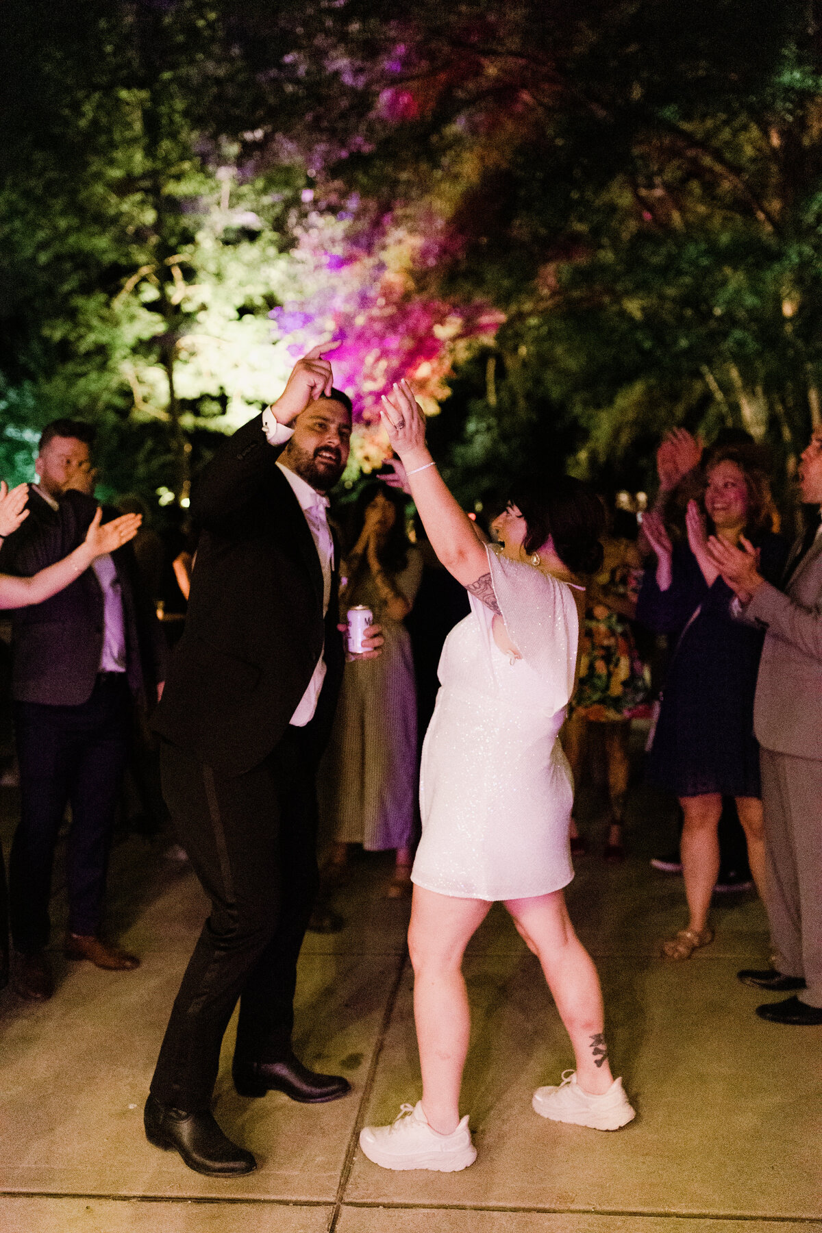 Bride in short white dress dancing at wedding reception with groom at Umlauf Sculpture Garden, Austin