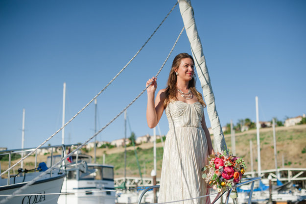 bride on a sailboat with bright florals and airbrushed makeup with a pink lip