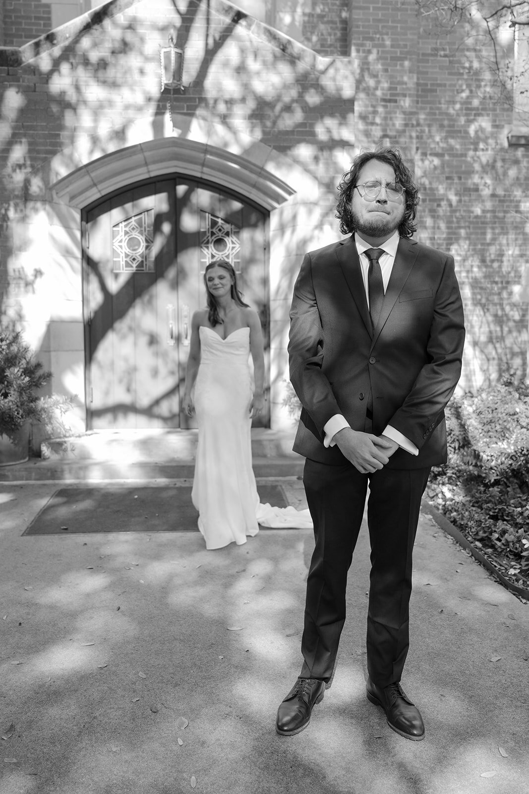 Stylish groom posed under dappled light archway at Texas luxury estate wedding before bride and groom first look