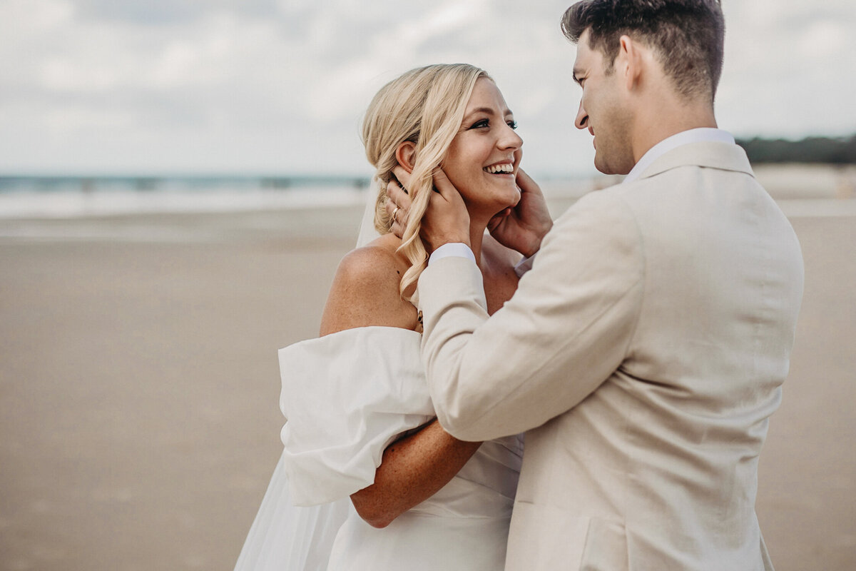 Romantic pose with bride and groom looking into each other's eyes by the sea