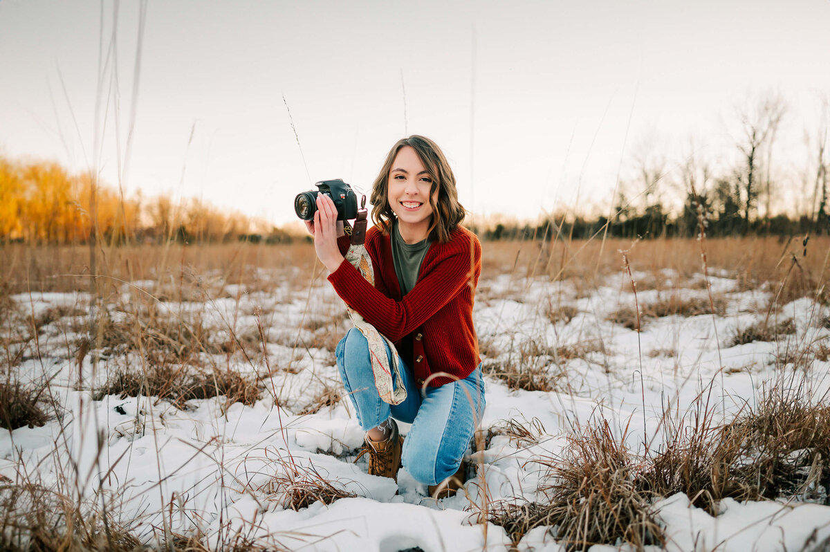 high school senior kneeling holding camera during Branson senior photography session