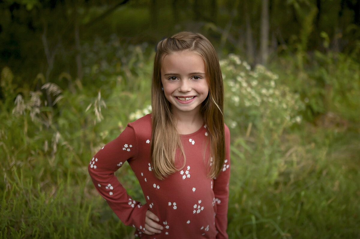 Young girl wearing red smiles with her hand on her hip