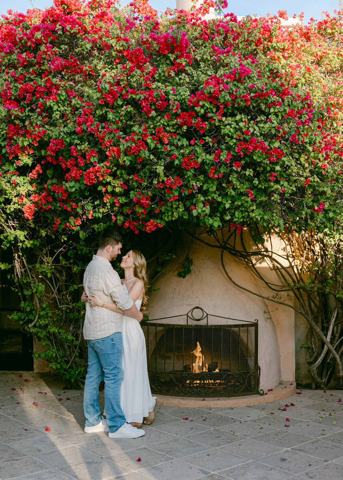 Couple hugging near the outdoor fireplace at Royal Palms Resort during golden hour engagement session
