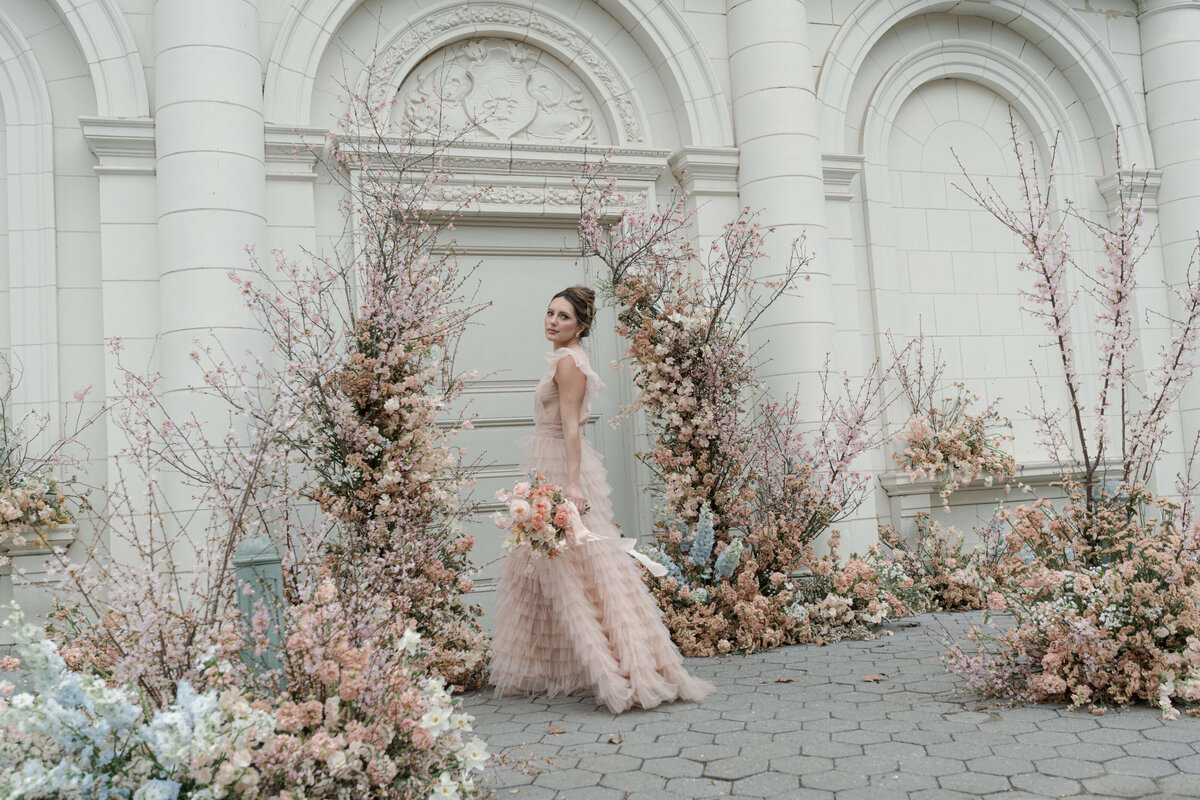 bride standing in middle of wedding arch