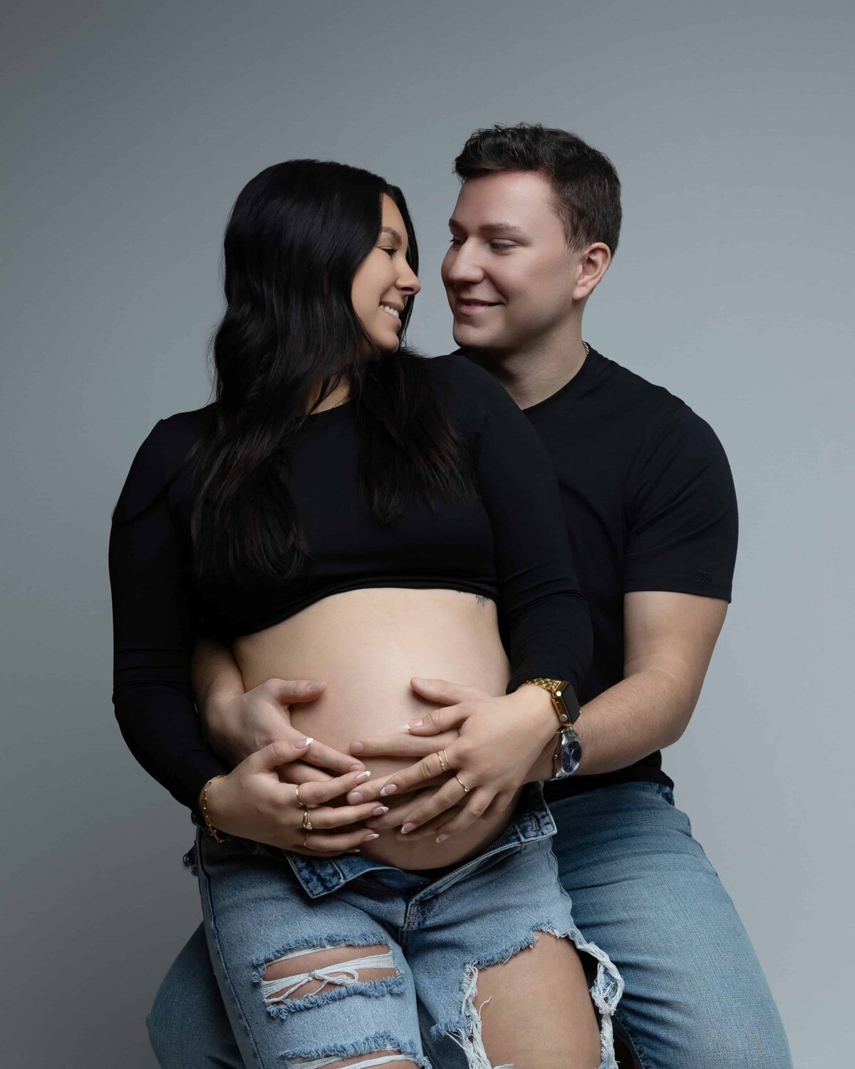 pregnant mom and dad laughing at eachother in studio