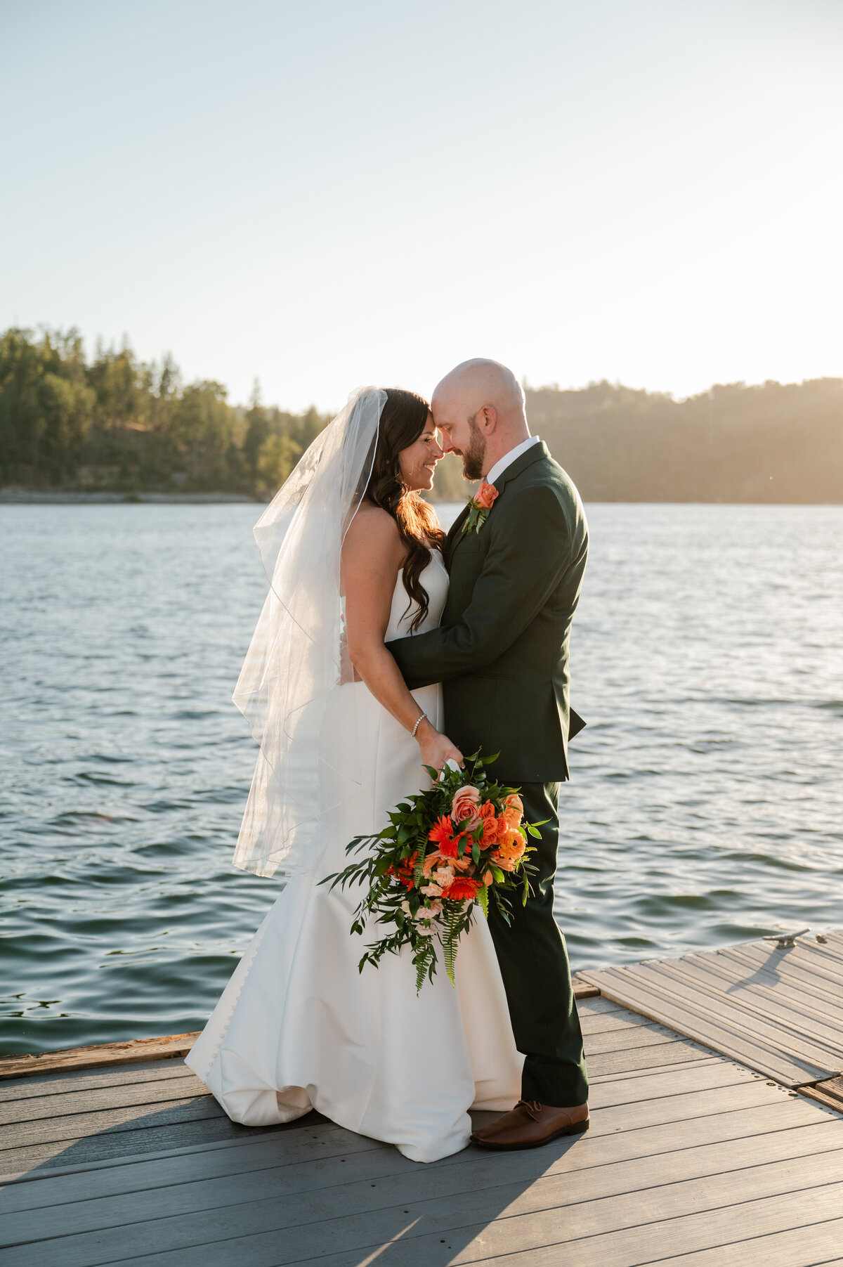 Bride and groom on the dock at The Pines Resort, with the lake and forest creating a picturesque backdrop.