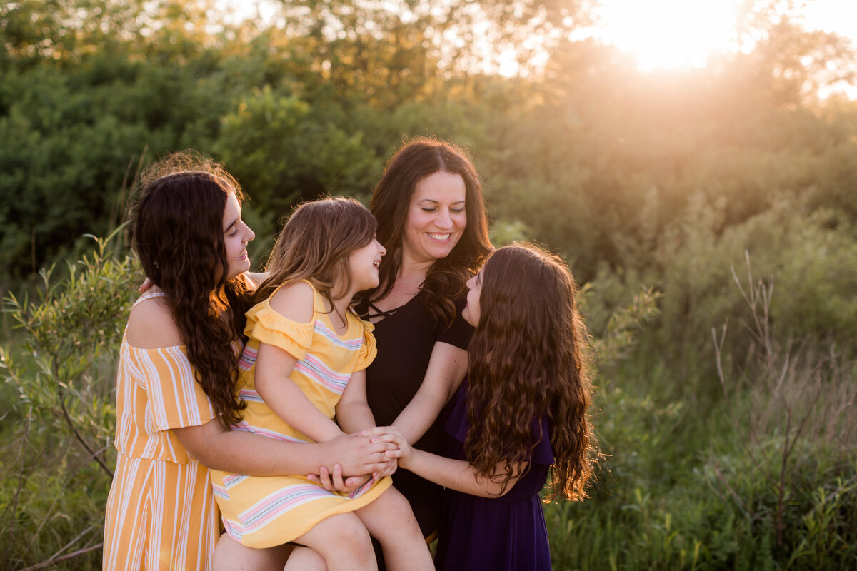 Mom and her girls tell each other jokes and laugh in the sunset In Joliet.