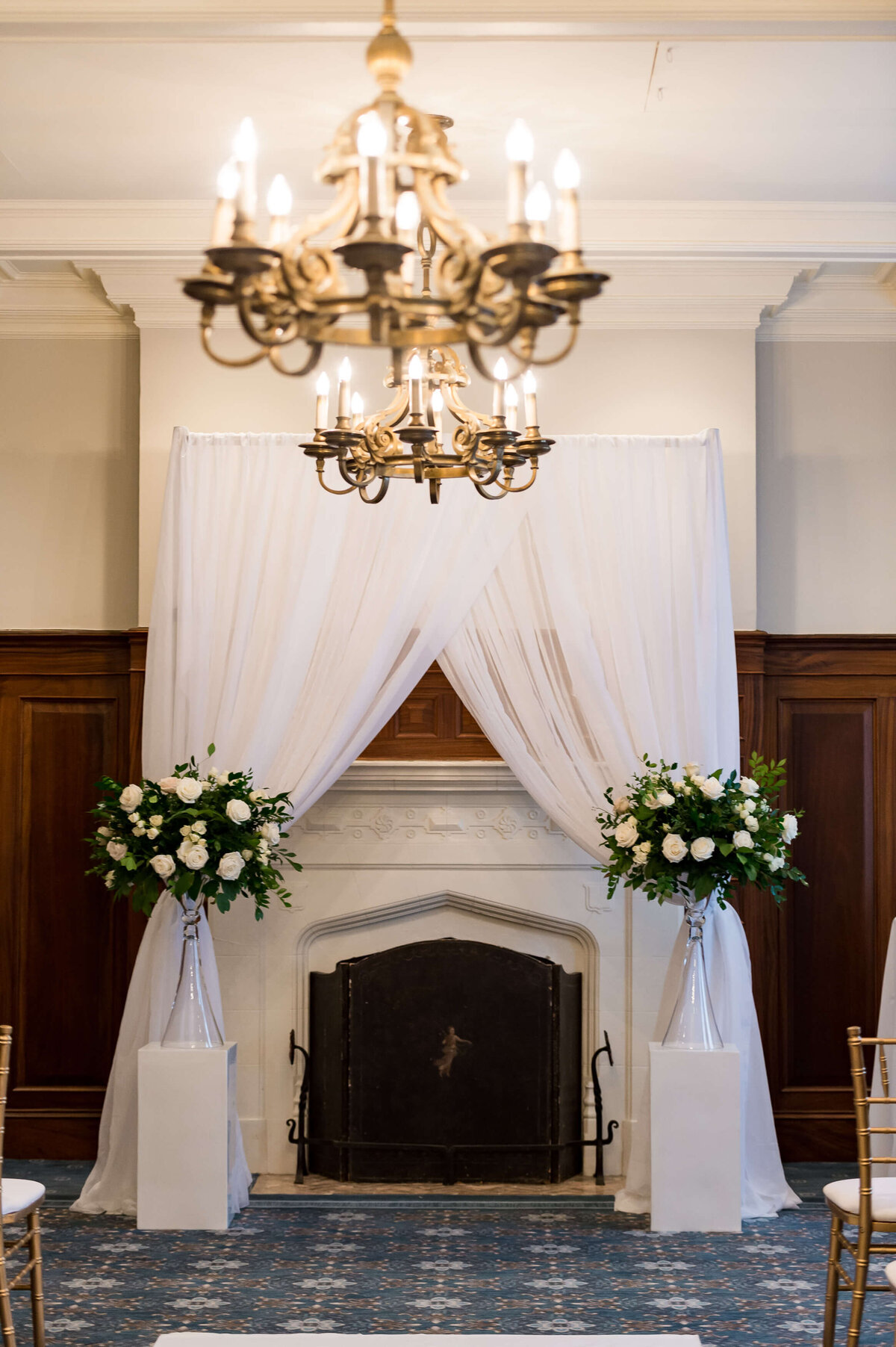 elegant Ottawa wedding ceremony decor with white draping, gold chandelier and white wedding flowers