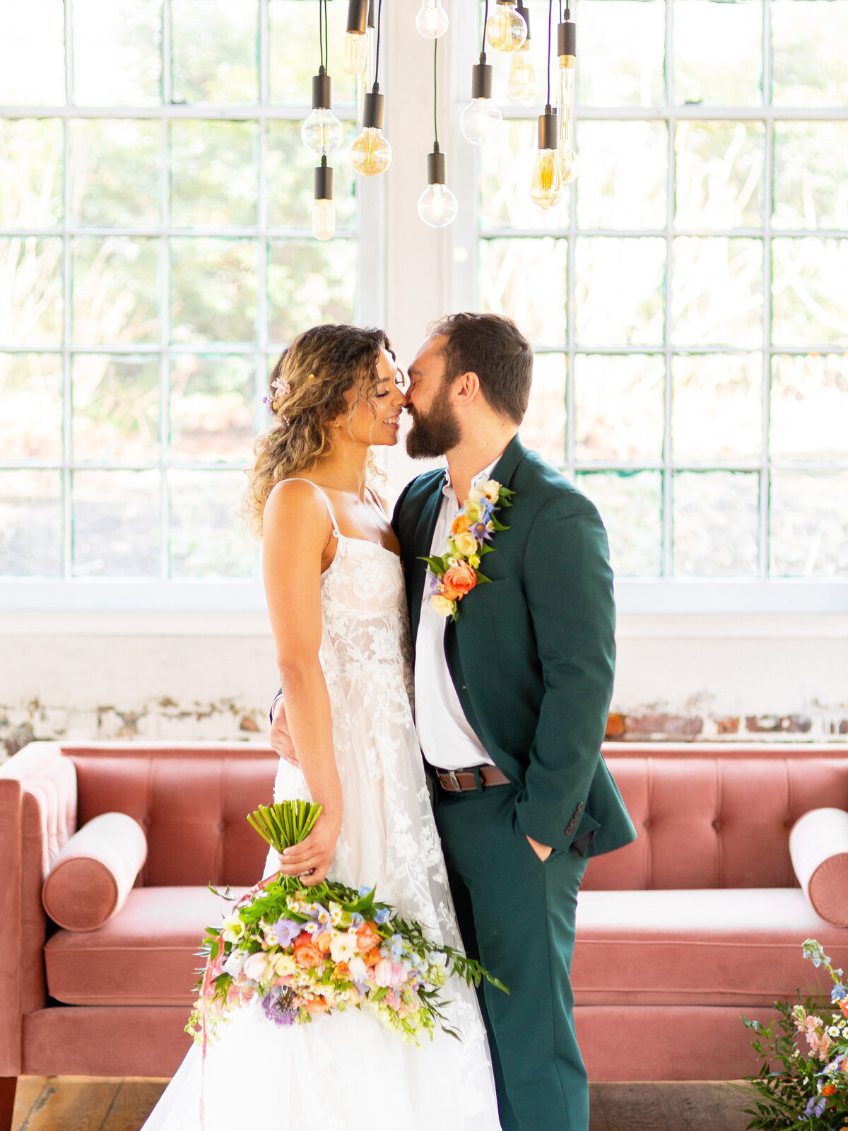 Bride and groom about to kiss in front of pink velvet couch