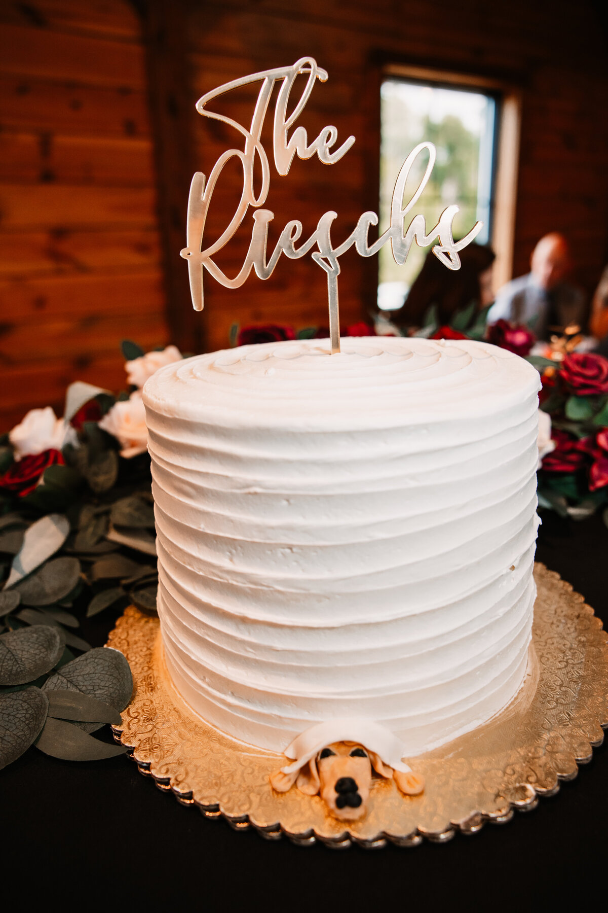A white cake with a dog at the bottom with a custom name topper