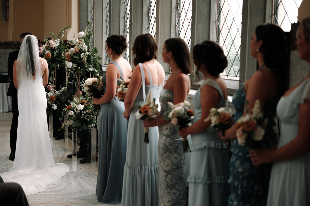 ceremony photo from the side with bridesmaids and back of brides dress shining in the light
