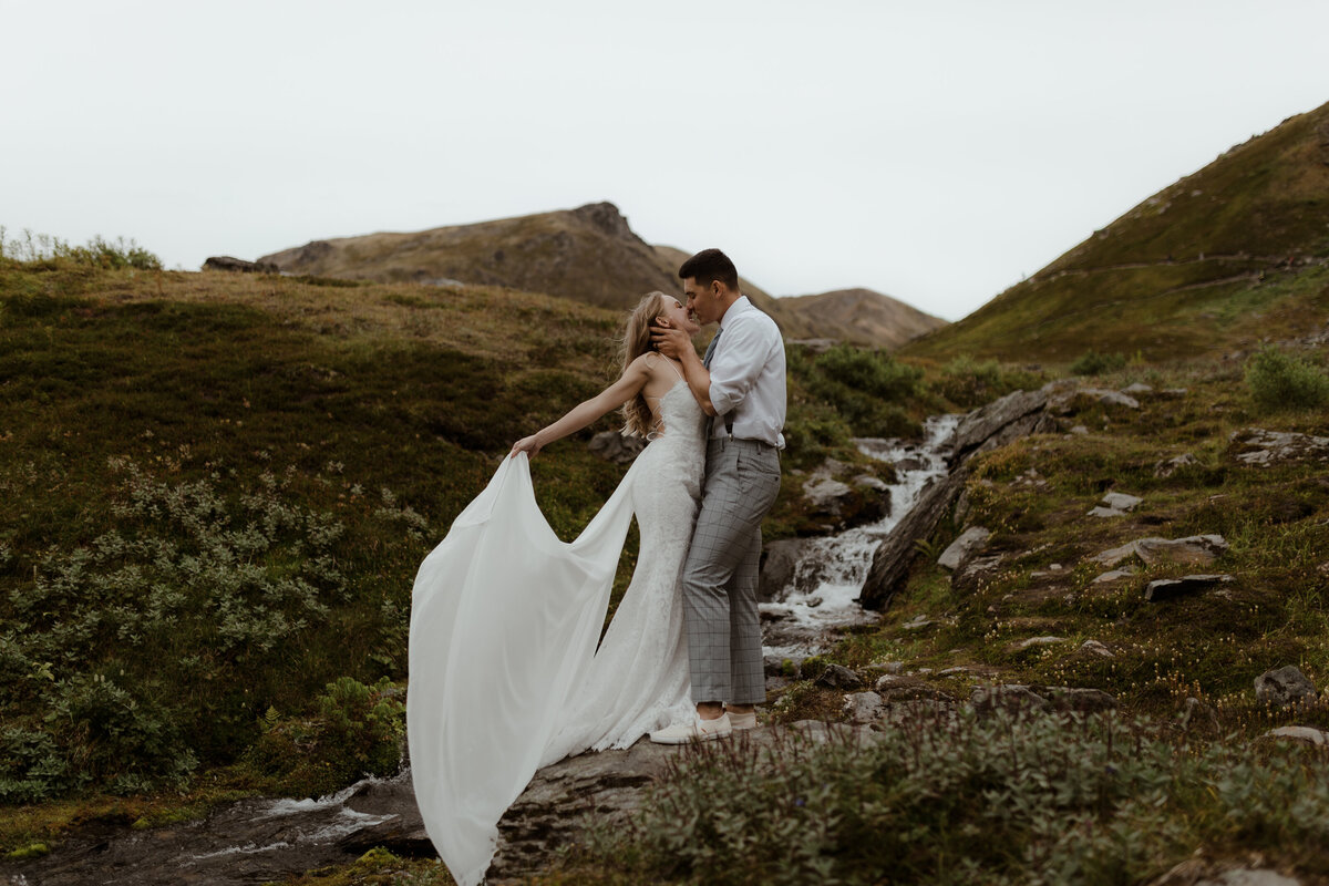 bride and groom kissing on hillside