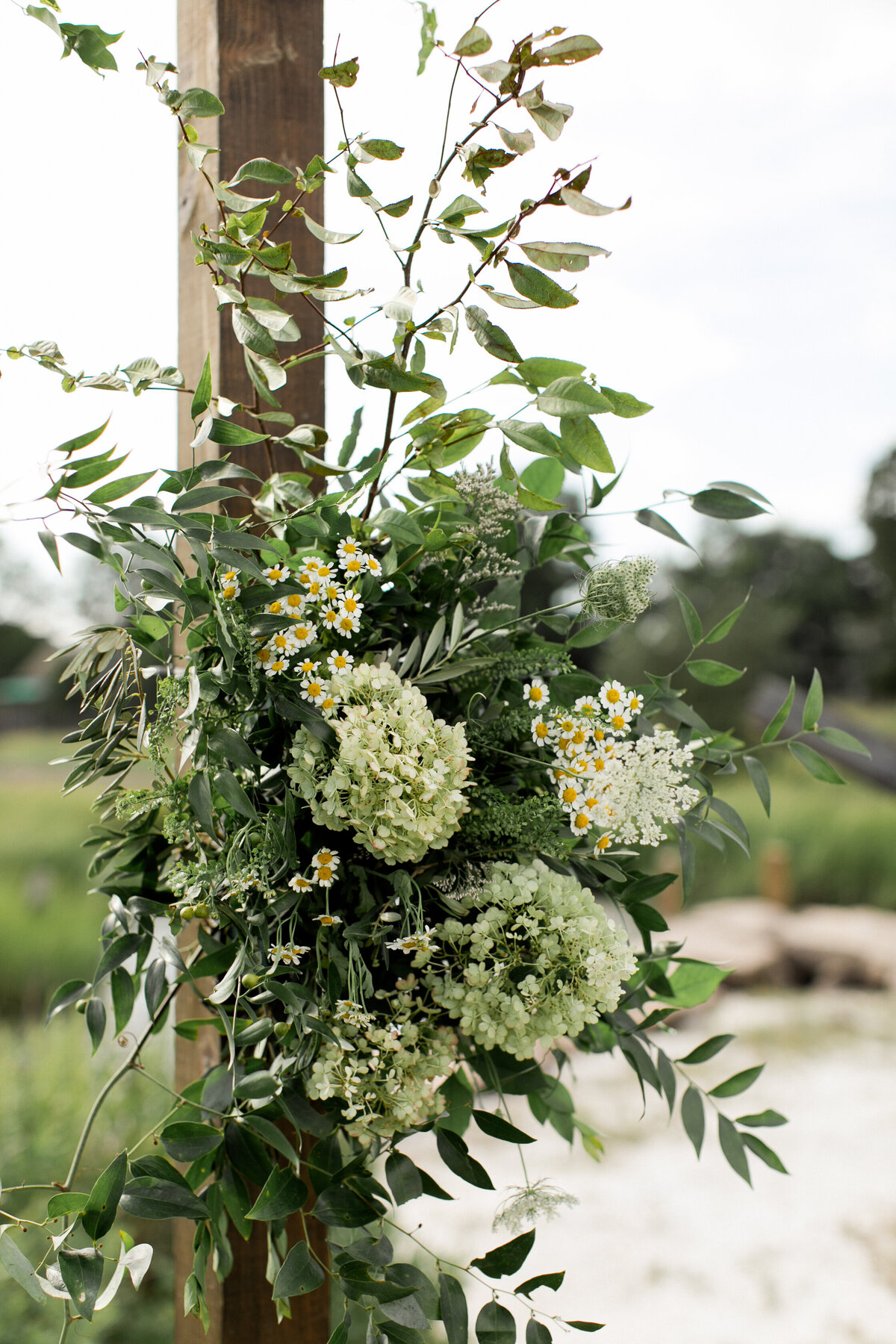 lush-greenery-waterfront-ceremony-lower-arrangements-pop-of-white