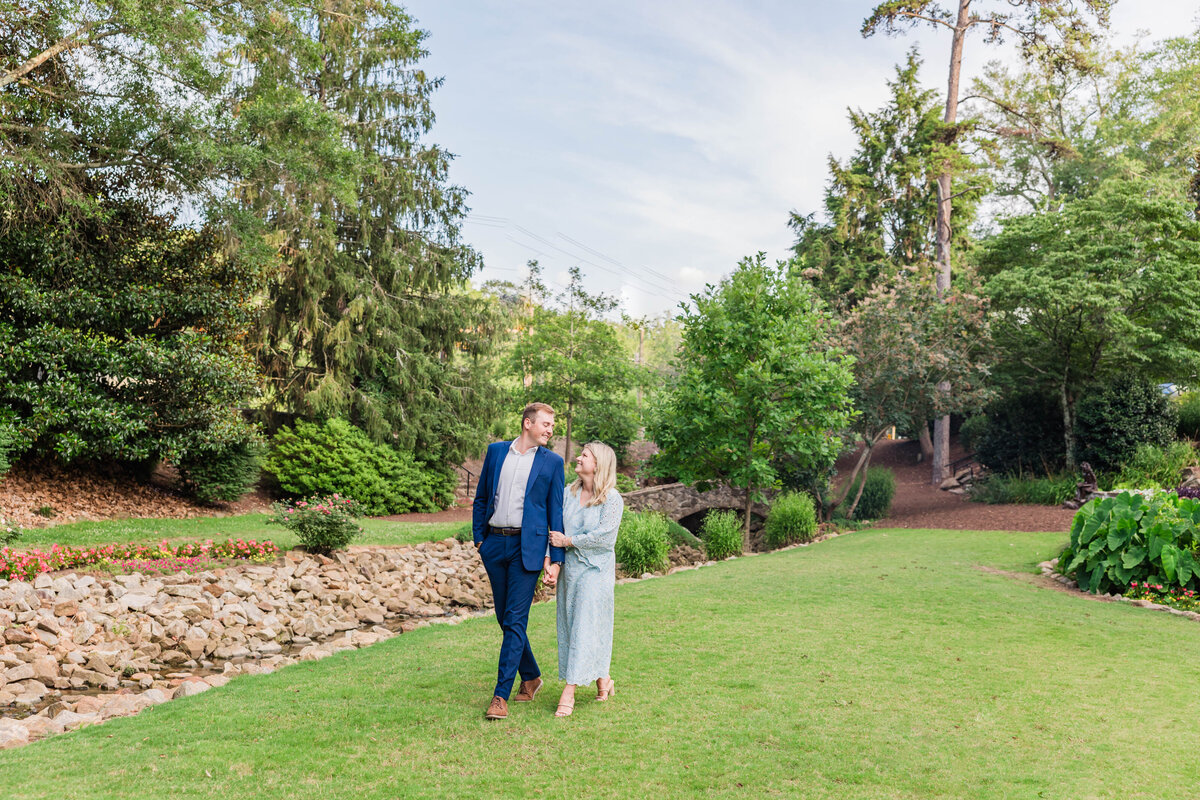 couple strolling hand in hand and gazing at each other with blue dress and navy suit