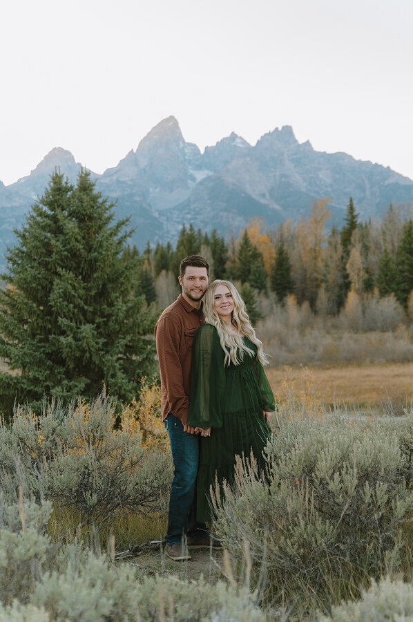 A couples session in Grand Teton National Park. A man is holding the hand of his fiancé from behind.