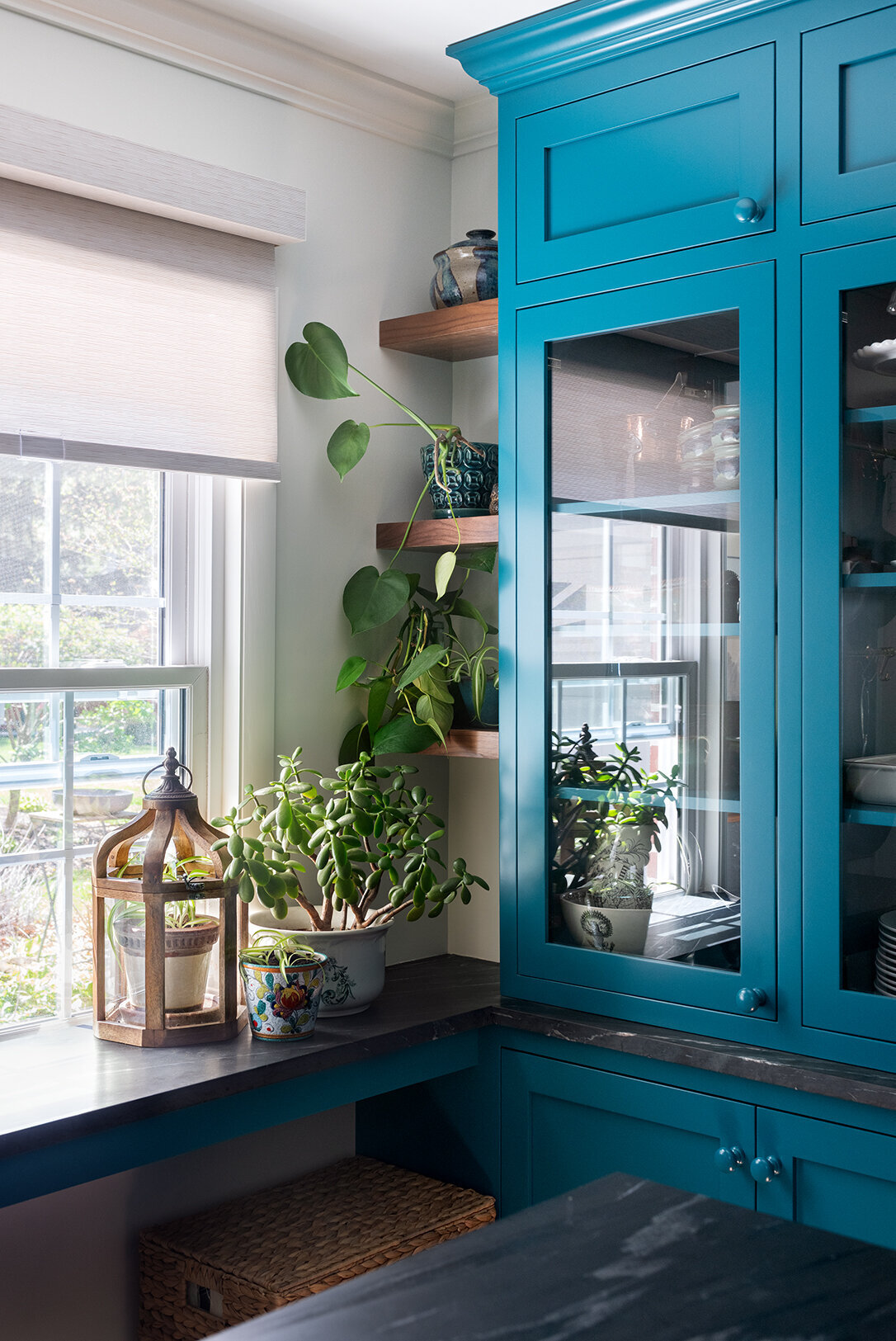 wooden open shelves with plants and teal china cabinet