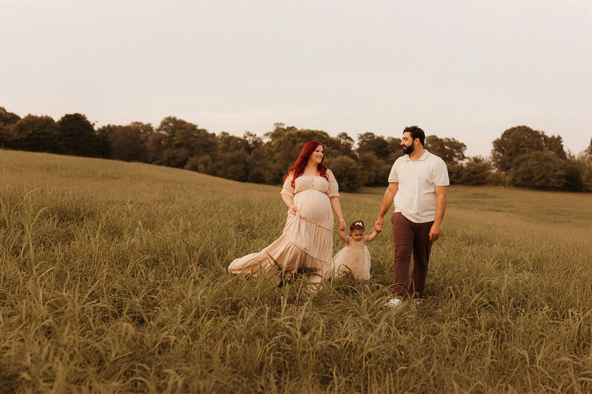 Expecting mother holding bump in flowing gown during Franklin TN sunset maternity session