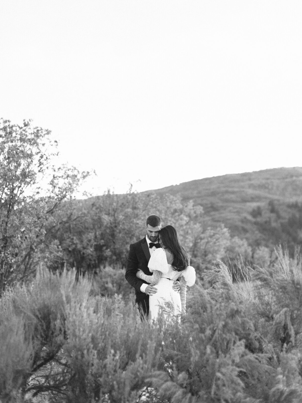 black-and-white-of-bride-and-groom-in-field-at-sunset