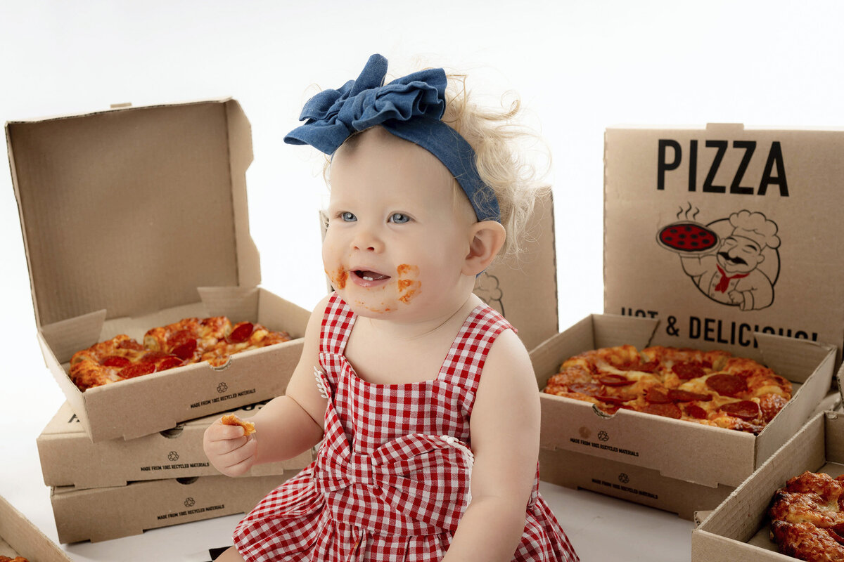 With pizza sauce on her face, a young girl smiles and looks to the side