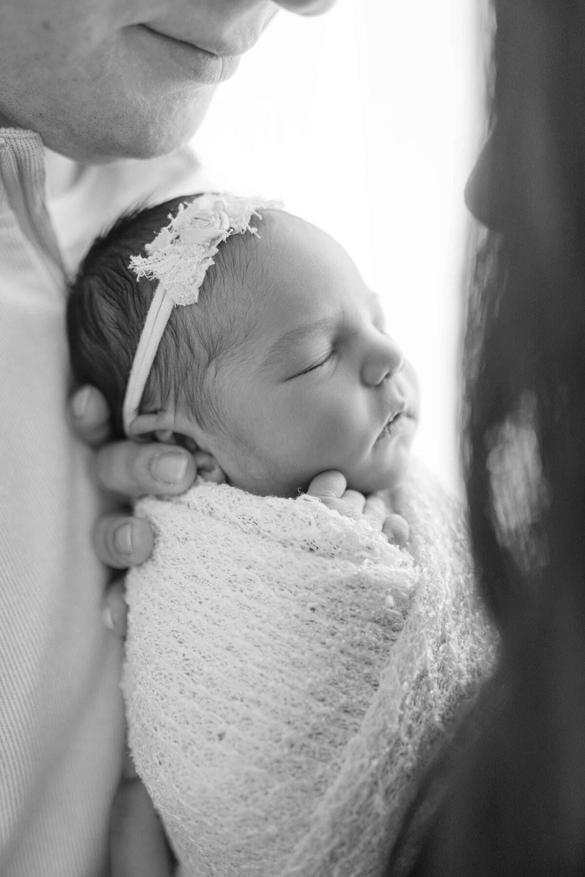 black and white portrait of newborn profile as she is tenderly held by her okc lawyer parents